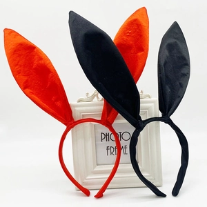 Detail view of orange and black satin bunny ear headbands leaning on a white frame