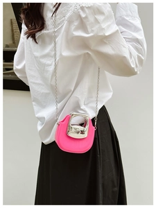 Pink mini crossbody bag with silver metal handle and chain strap worn by a model