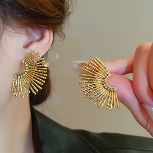 Detail of gold fan-shaped flower earrings with sparkling rhinestones and metal texture
