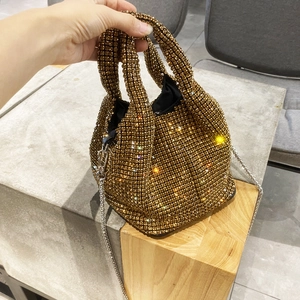 Close-up of gold rhinestone bucket bag with silver chain strap and sparkling crystals