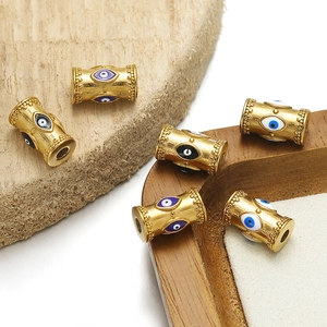 Macro detail of gold evil eye beads with colorful enamel on textured wood base