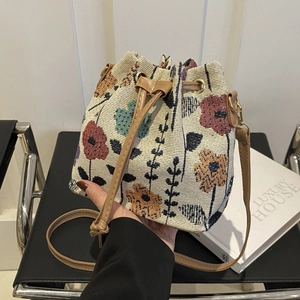 Beige woven bucket bag with floral patterns, leather drawstring and long shoulder strap