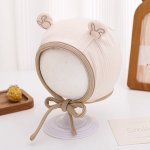 Détail du bonnet bébé en coton rose avec cache-oreilles, broderie et lanières