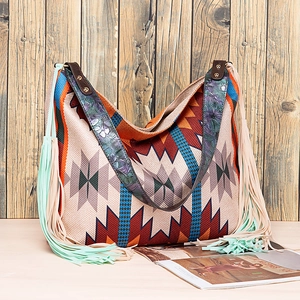 Close-up of bohemian tote bag with fringe tassels and embossed floral leather strap