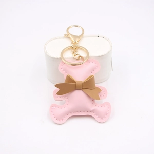 Detail shot of a pink PU leather bear keychain with a brown bow and gold metal clasp