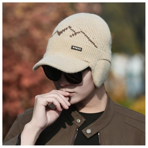 Detail of beige winter knit hat featuring mountain pattern and leather NY&JA brand patch