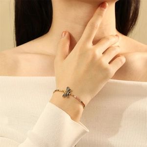Elegant gold chain bracelet with a colorful gemstone dragonfly charm on a female model