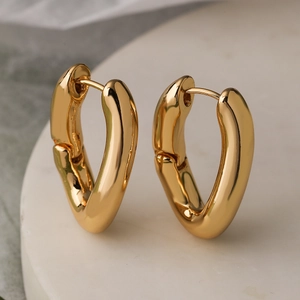 Minimalist irregular geometric gold-plated earrings on white marble display stand