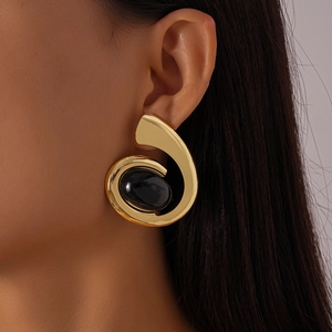 Vue macro de boucles d'oreilles spirales dorées avec de grandes pierres ovales noires