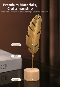 Detail of gold metal feather sculpture on a solid wood base for modern luxury decor