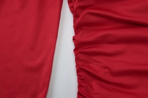Gros plan sur un tissu en maille rouge avec détails froncés et texture plissée