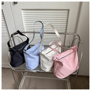 Sacs cabas minimalistes en nylon noir, bleu, beige et rose sur un support métallique