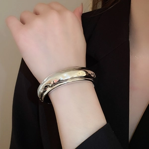 Gros plan d'un large bracelet manchette argenté au design de métal liquide irrégulier