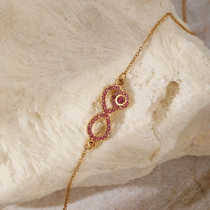 Close-up of golden infinity symbol necklace with shimmering pink rhinestones detail