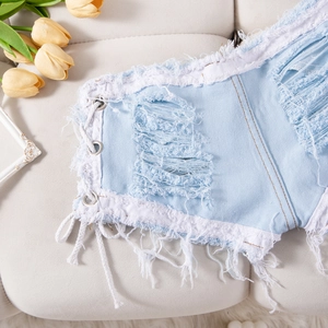 Detalle de shorts vaqueros azul claro con rotos marcados, bajos deshilachados y cordones laterales