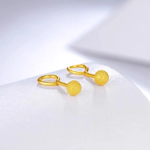 Macro shot of minimalist matte gold ball stud earrings with detailed sandblasted finish