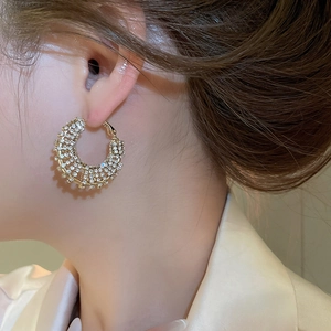 Detail of elegant gold C-shaped earrings with sparkling crystals worn by a model