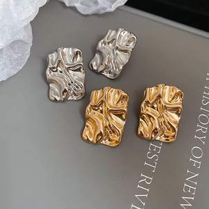 Detailed view of silver and gold irregular crumpled geometric earrings with liquid metal texture
