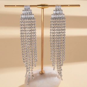Close-up of silver long tassel earrings with sparkling rhinestones on a display stand