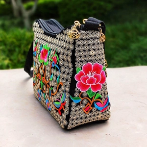 Close-up of vibrant floral embroidery and gold hollow zippers on ethnic crossbody bag