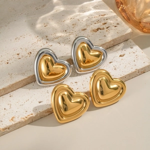 French vintage gold and silver heart stud earrings on decorative stone display