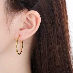 Close-up of classic golden stainless steel hoop earring worn by a model for a chic look