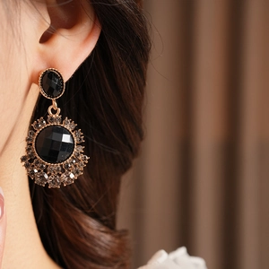 Gros plan détaillé d'une boucle d'oreille vintage dorée avec pierres noires sur un modèle