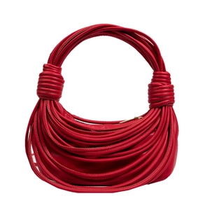 Dettaglio della borsa rossa in pelle intrecciata con nodi e tracolla a corda