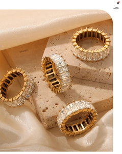 Detail of four gold-plated eternity rings with emerald-cut cubic zirconia on satin fabric