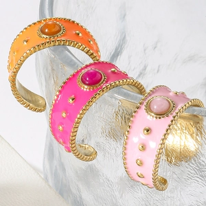 Detailed view of colorful enamel bangles with gold bead edges and inlaid gemstones