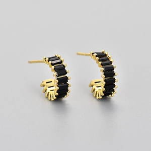 Macro shot of gold-plated C-shaped earrings featuring faceted square black zircon stones