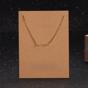 Detailed view of the gold Mama letter necklace displayed on a brown kraft card holder