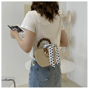 Straw shell bag with brown pleated handle, silk scarf detail, and model shoulder carry