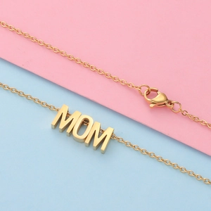 Κοντινό πλάνο χρυσού κολιέ με μενταγιόν MOM και κούμπωμα σε πολύχρωμο φόντο