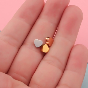Mirror polished heart beads in silver, gold, and rose gold on a finger for size