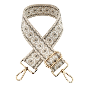 Détail de la bandoulière jacquard beige de 5 cm avec motifs géométriques gris et clips dorés