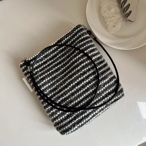 Detail of striped knit crossbody bag featuring a simple wish label and black leather strap