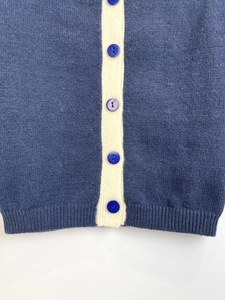 Close-up of contrast knit cardigan with navy buttons and ribbed hem details
