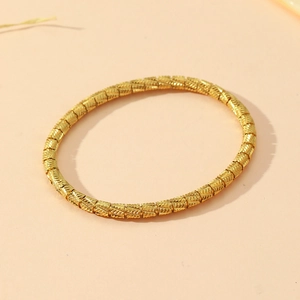 Detailed view of a golden stainless steel bracelet with a segmented bamboo texture