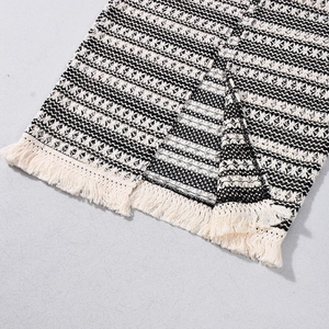 Détail de tissu tricoté bohème avec tissage noir et blanc et bordure à franges crème