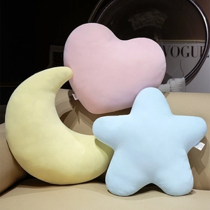 Coussins en peluche étoile lune et cœur aux couleurs pastel sur un canapé doux
