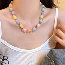 Detail of colorful heart-shaped beaded necklace with silver spacers on a female model