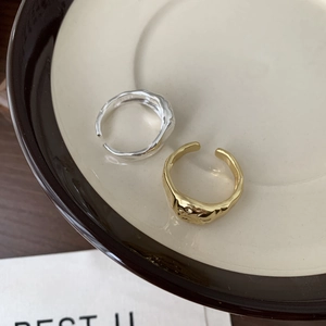 Detail of minimalist irregular texture open rings in gold and silver on ceramic plate