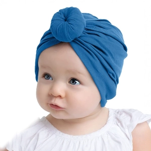 Close-up of a newborn wearing a soft blue donut-style knot hat in breathable fabric