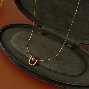 Detail of tiger eye pendant in U-shaped gold setting on black velvet jewelry box