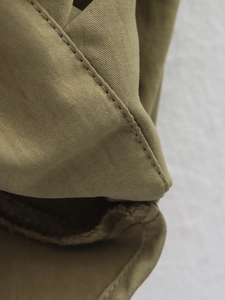 Gros plan des coutures et de la texture du tissu sergé kaki sur la veste bomber