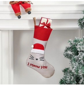 Hanging beige cat Christmas stocking with Meow embroidery on a festive fireplace
