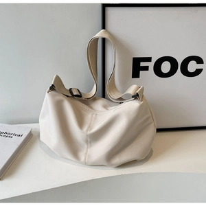 Detail of cream-colored nylon tote bag featuring a wide strap and adjustable buckle