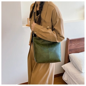 Dark green minimalist PU leather tote bag worn by model in a stylish home setting