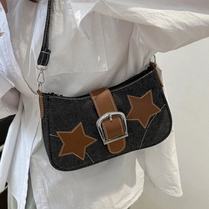Detail of black denim shoulder bag with brown star patches and silver metal buckle